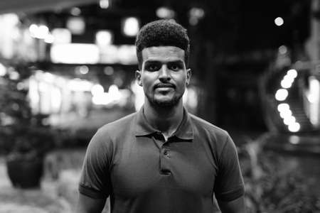 Portrait of young handsome black man in city at nightの写真素材