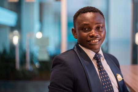Portrait of handsome young African man in office at nightの写真素材
