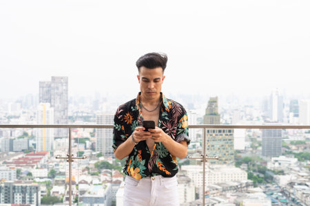 Portrait of handsome young cool man in city texting with phone