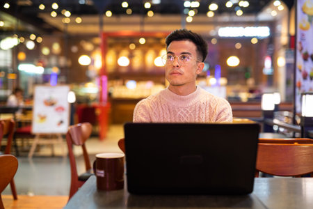 Portrait of handsome young man using laptop computer at coffee shopの写真素材