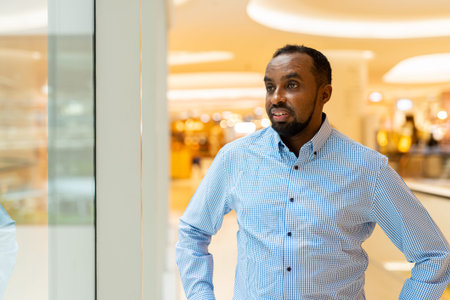 Black man looking through window while thinking