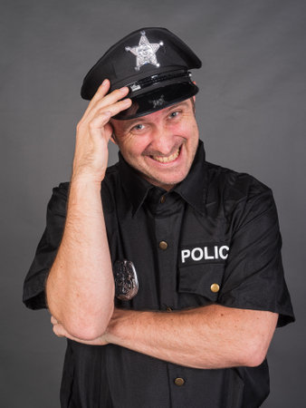 Portrait of Caucasian man wearing police uniform costume against gray studio backgroundの写真素材