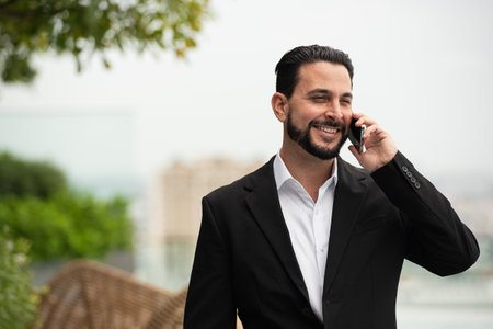 Portrait of handsome businessman outdoors at rooftop talking on mobile phone horizontal shotの写真素材