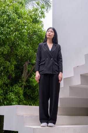 Full body portrait of a professional woman in business attire exuding confidence on modern architectural steps including greeneryの写真素材