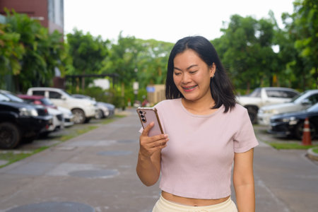 Portrait of beautiful Asian woman outdoors during summer using mobile phone