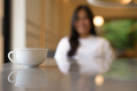 Coffee Cup in Focus with Smiling Young Thai Woman in Background Conceptの写真素材