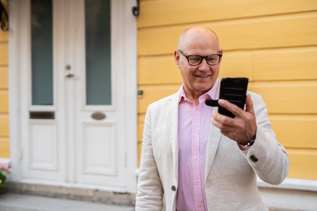 Happy Scandinavian Senior Man Using Phone Outdoors in Summer Joyful Technology Use Conceptの写真素材