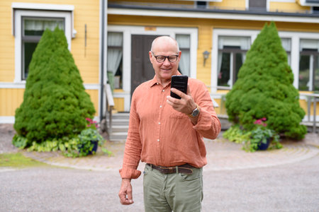 Senior Finnish Man Using Mobile Phone Outdoors During Autumn Conceptの写真素材