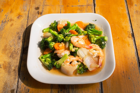 Shrimps with broccoli and carrots served on outdoors tableの写真素材