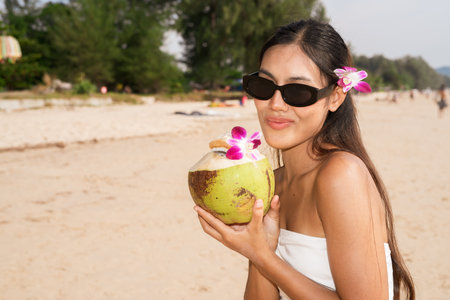 Young beautiful Asian woman smiling with coconut on beachの写真素材