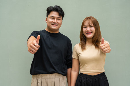 Portrait of young Asian couple against plain wallの写真素材