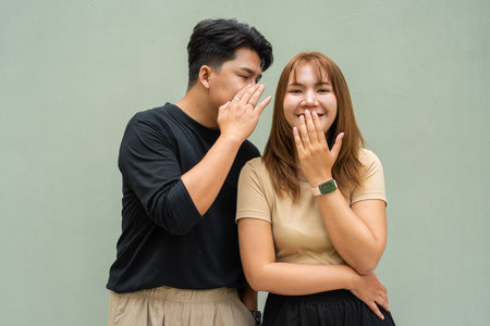 Portrait of young Asian couple against plain wallの写真素材