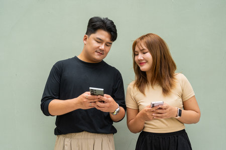 Portrait of young Asian couple against plain wallの写真素材