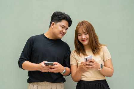 Portrait of young Asian couple against plain wallの写真素材