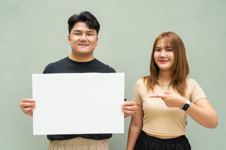 Portrait of young Asian couple against plain wallの写真素材
