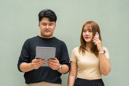 Portrait of young Asian couple against plain wallの写真素材