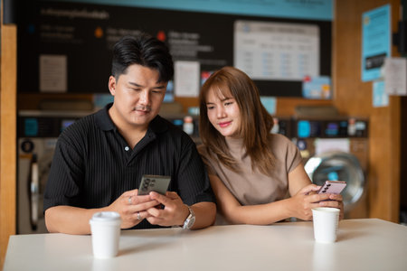 Young confident Asian couple in laundry shopの写真素材