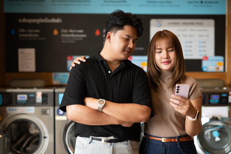 Young confident Asian couple in laundry shopの写真素材