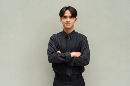 Young Asian businessman portrait against plain wall with copy spaceの写真素材