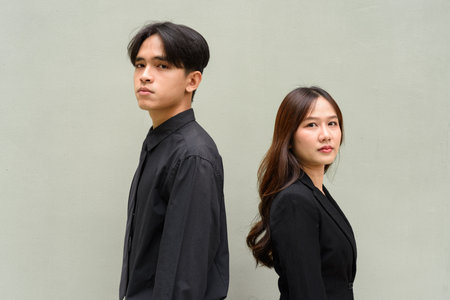 Portrait of young Asian couple wearing business uniform against plain backgroundの写真素材
