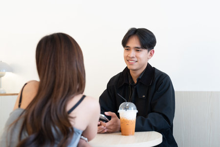 Young happy Asian couple sitting in coffee shop date together indoorsの写真素材