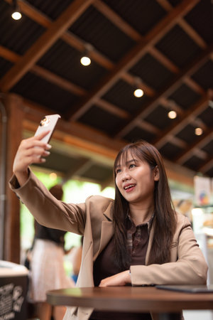 young Asian woman in cafe taking selfieの写真素材