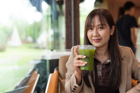 young Asian woman drinking green detox juice in cafe