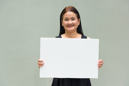 Portrait of Asian mature woman against plain wall background