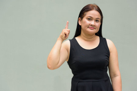 Portrait of Asian mature woman against plain wall backgroundの写真素材