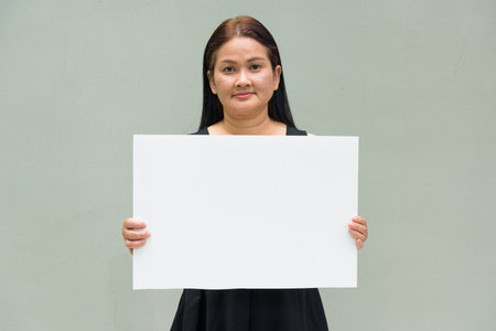 Portrait of Asian mature woman against plain wall backgroundの写真素材