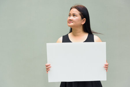 Portrait of Asian mature woman against plain wall backgroundの写真素材