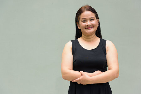 Portrait of Asian mature woman against plain wall backgroundの写真素材