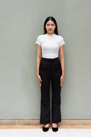 Portrait of young Asian woman standing wearing business clothes against plain office wall outdoorsの写真素材