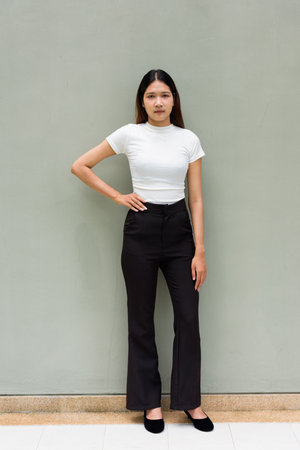 Portrait of young Asian woman standing wearing business clothes against plain office wall outdoorsの写真素材