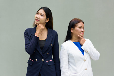 Portrait of mother and daughter against plain wall background