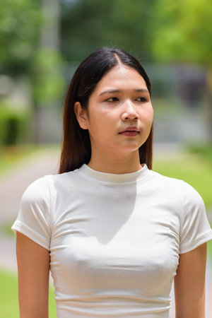 Portrait of Asian woman outdoors in park during sunny dayの写真素材