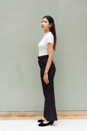 Portrait of young Asian woman standing wearing business clothes against plain office wall outdoorsの写真素材