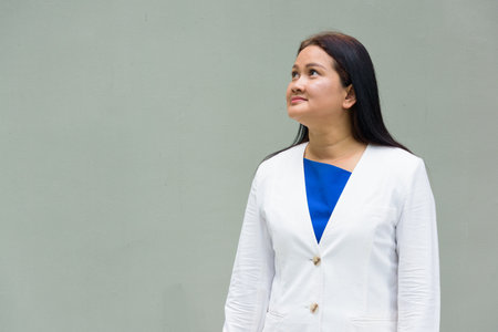 Portrait of mature Asian woman against plain wallの写真素材