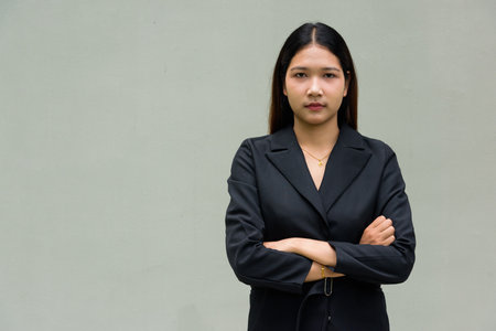 Portrait of young Asian businesswoman against plain backgroundの写真素材