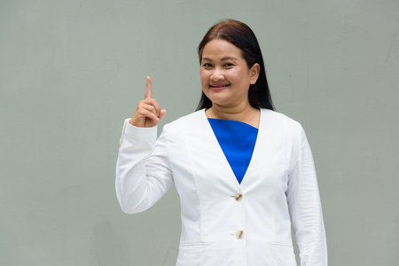 Portrait of mature Asian woman against plain wallの写真素材