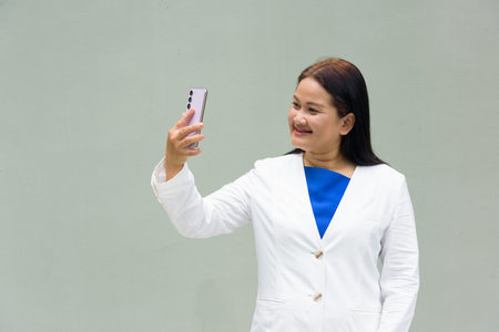 Portrait of mature Asian woman against plain wall