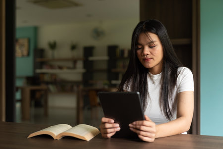 Young Asian student woman using digital tablet in library