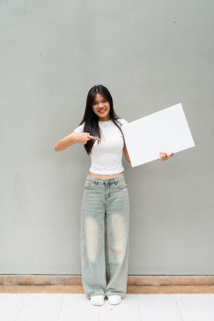 Full length portrait of Asian woman outdoors against plain wall background vertical shotの写真素材