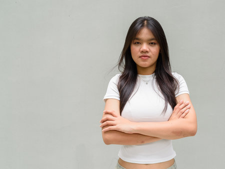 Portrait of beautiful young Asian woman against plain wall backgroundの写真素材
