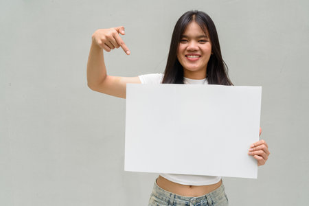 Portrait of young Asian woman against plain wall backgroundの写真素材