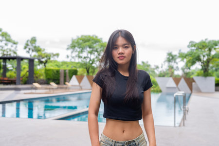 Young beautiful Asian woman relaxing next to swimming pool during summer
