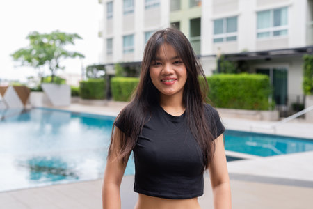 Young beautiful Asian woman relaxing next to swimming pool during summerの写真素材