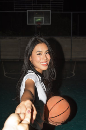 Young beautiful woman at night in basketball court posingの写真素材