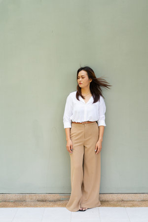 Full length portrait of woman wearing business clothes against plain wallの写真素材
