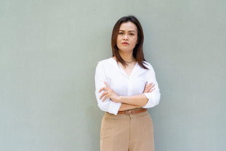 Portrait of beautiful Asian businesswoman against plain wall backgroundの写真素材